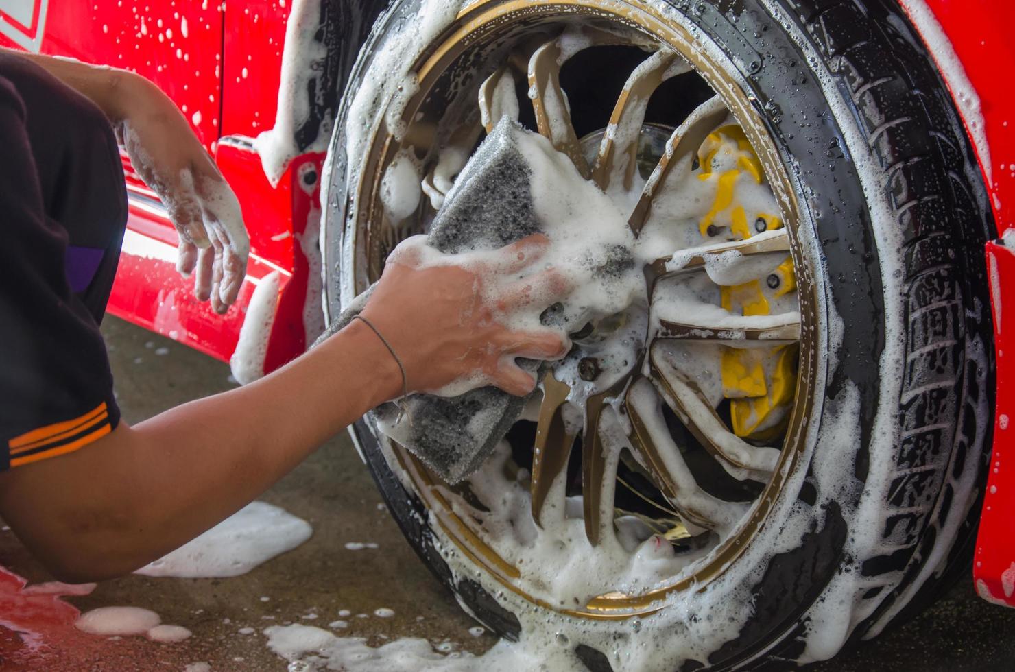 Waschen der Reifen eines roten Autos foto
