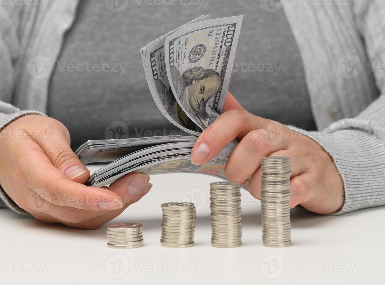 Stapel von Münzen auf Weiß chtoli und weiblich Hände sind halten ein Stapel von Papier amerikanisch Dollar. das Konzept von Budget Kontrolle, Akkumulation, profitieren Herstellung foto