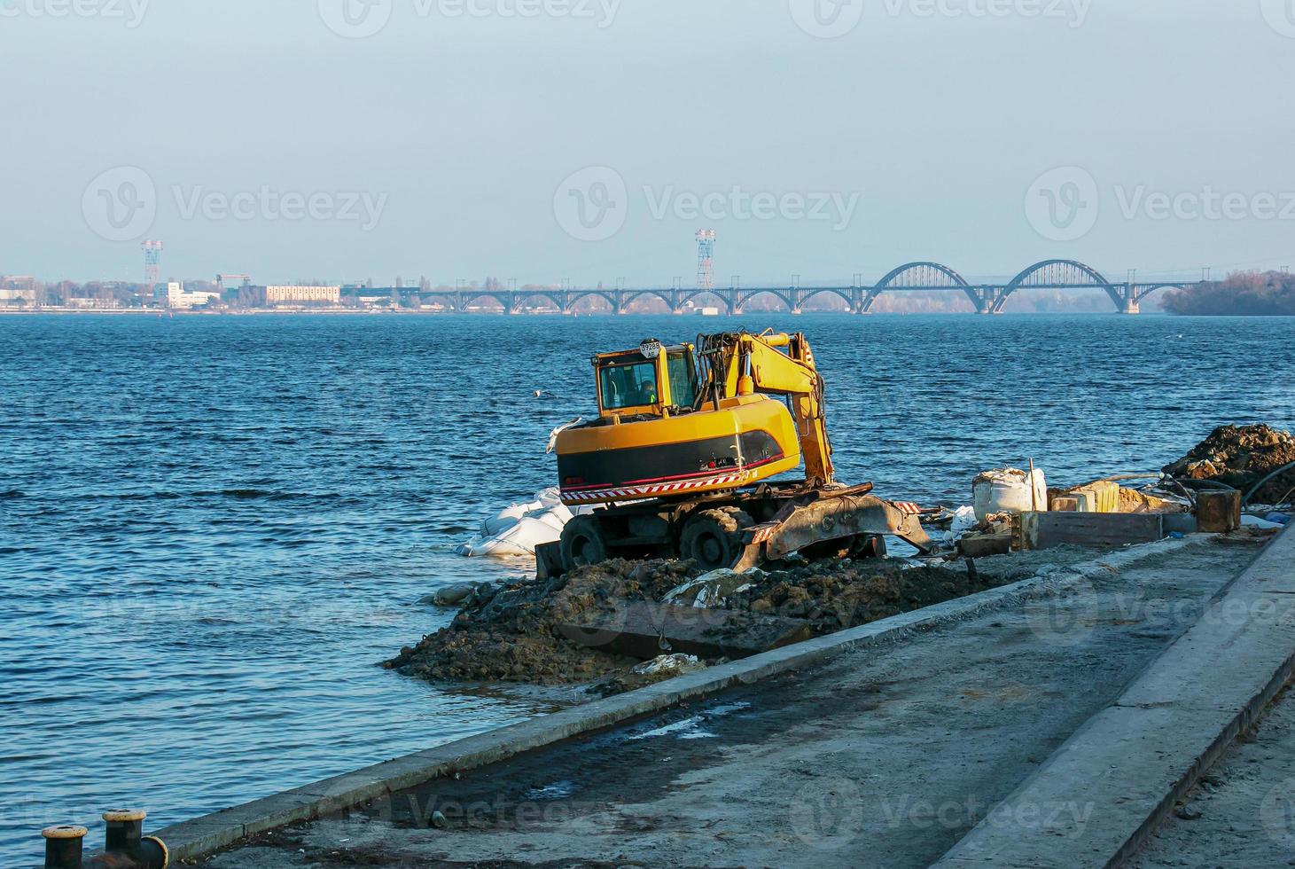 Bagger arbeitet, um die Böschung zu stärken. Hydraulikbagger, der am Flussufer arbeitet. foto