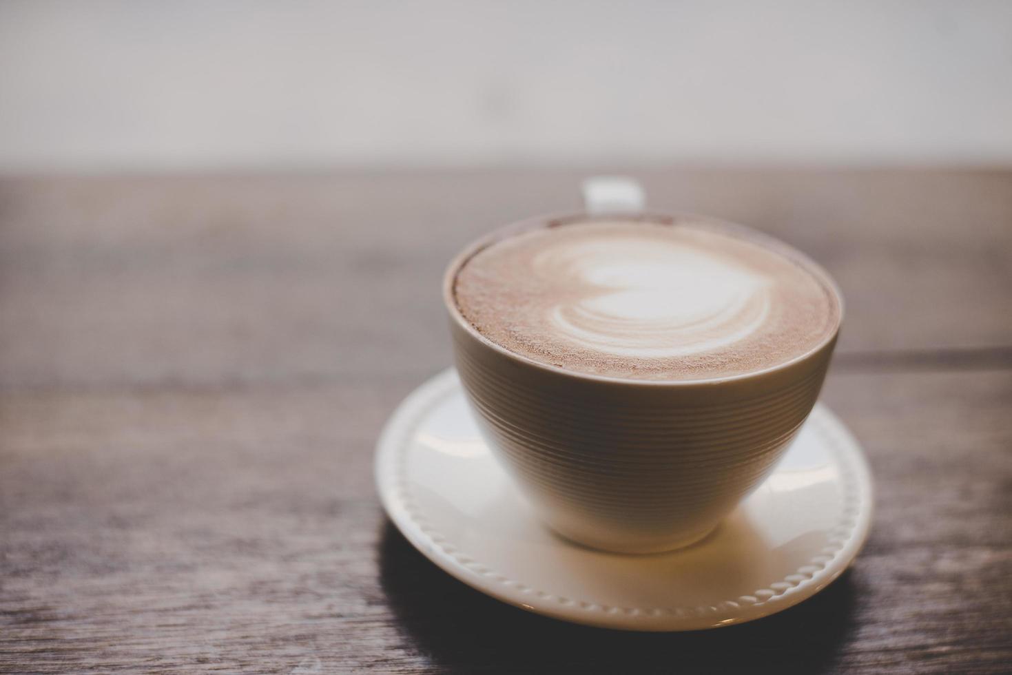 Vintage Latte Art Kaffee mit Herzform auf Holztisch foto