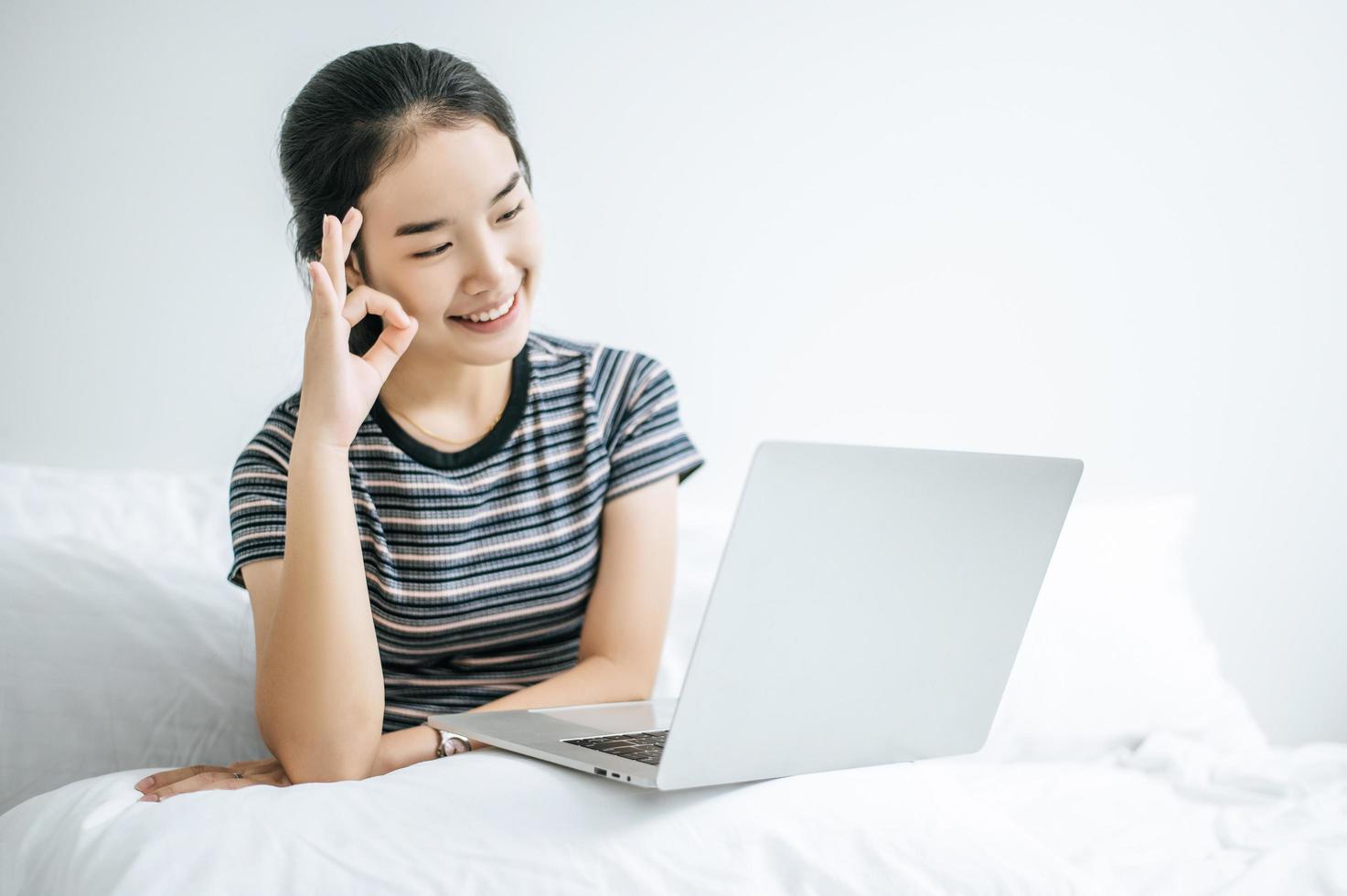 eine junge Frau spielt auf ihrem Laptop im Bett foto