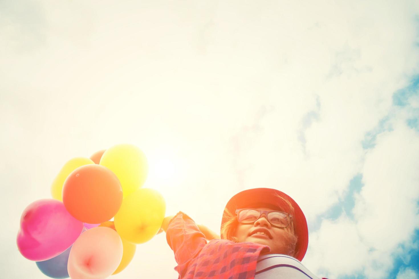 junge Hipsterfrau, die Luftballons unter dem Himmel hält foto