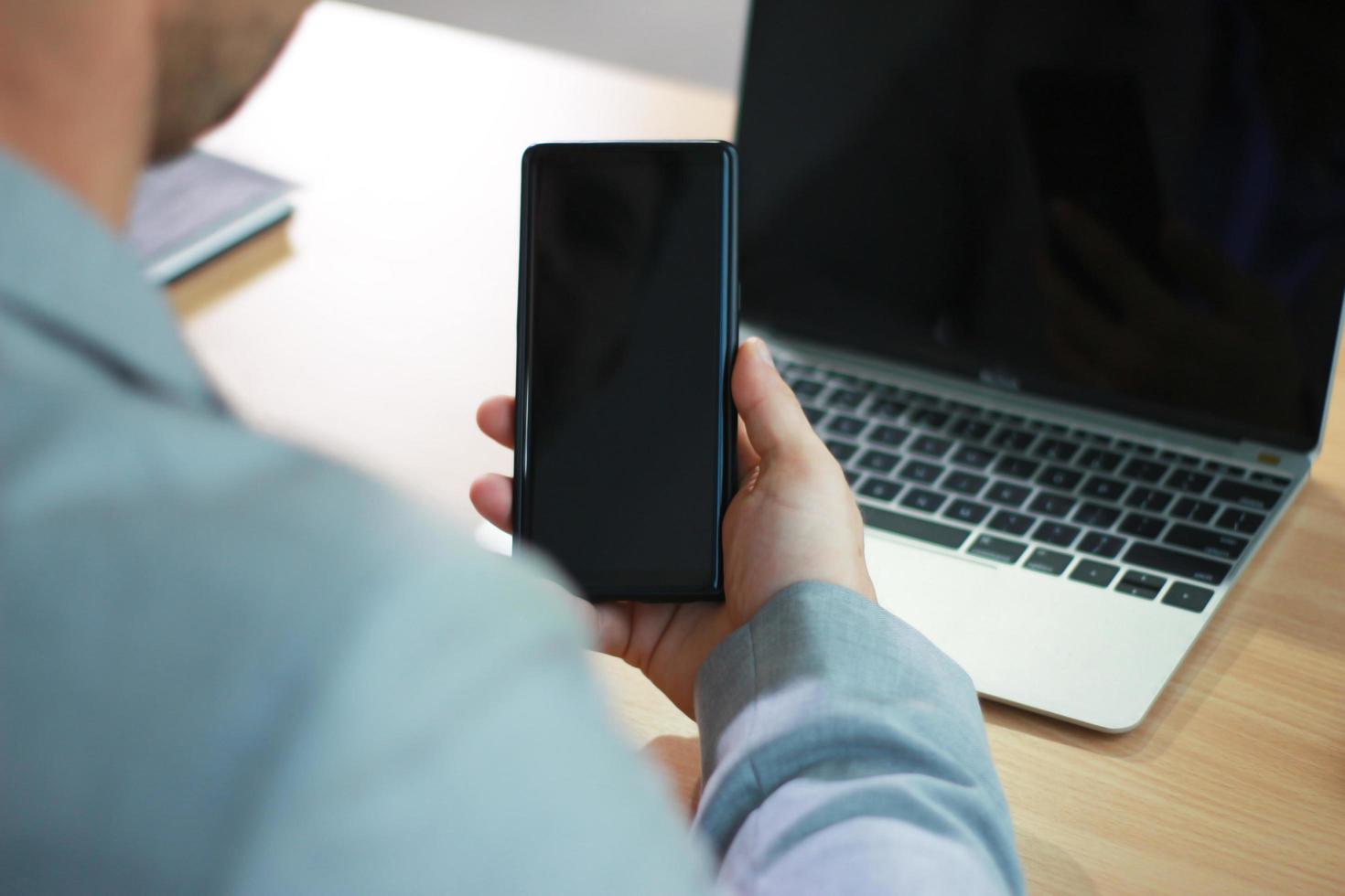 Mann mit Smartphone und Laptop-Modell foto