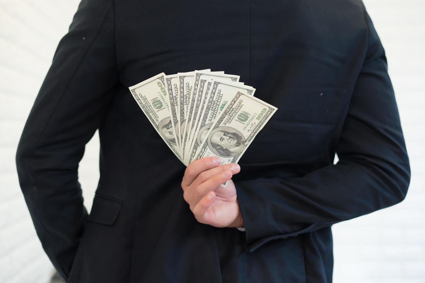 Porträt eines Geschäftsmannes, der Geld hält und es versteckt foto