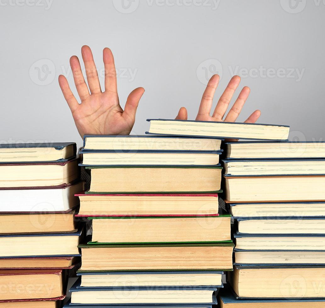 ein Stapel von anders Bücher auf ein grau Hintergrund, zwei weiblich Hände foto