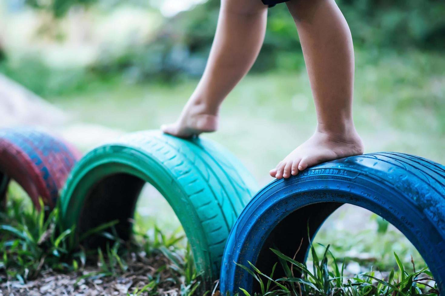 Kind läuft auf Reifen auf dem Spielplatz foto