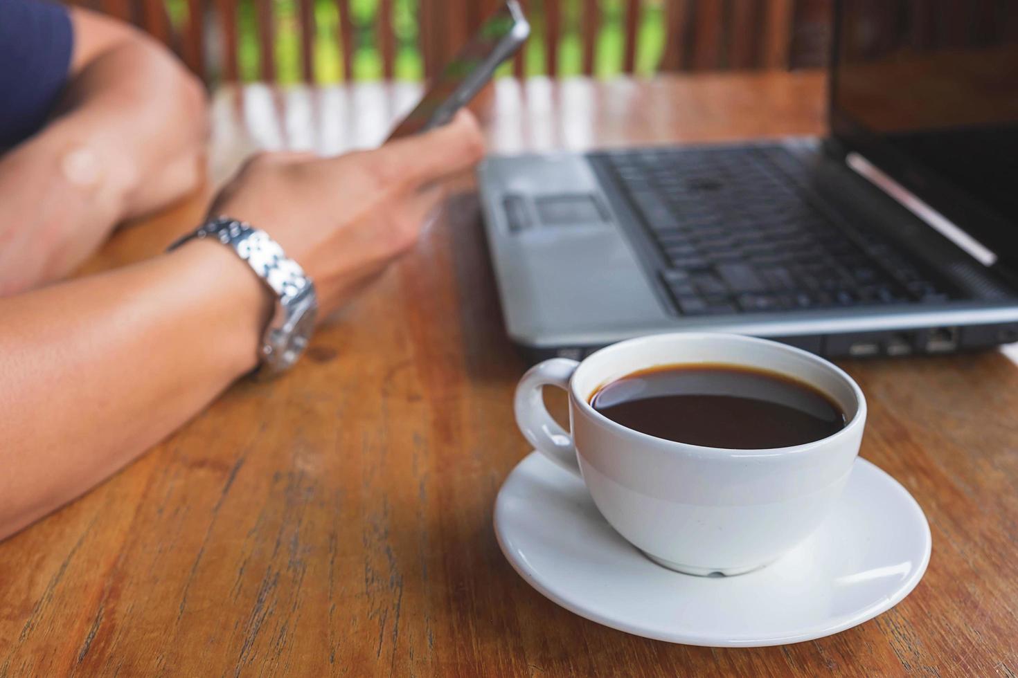 Person, die an einem Schreibtisch mit einem Kaffee arbeitet foto