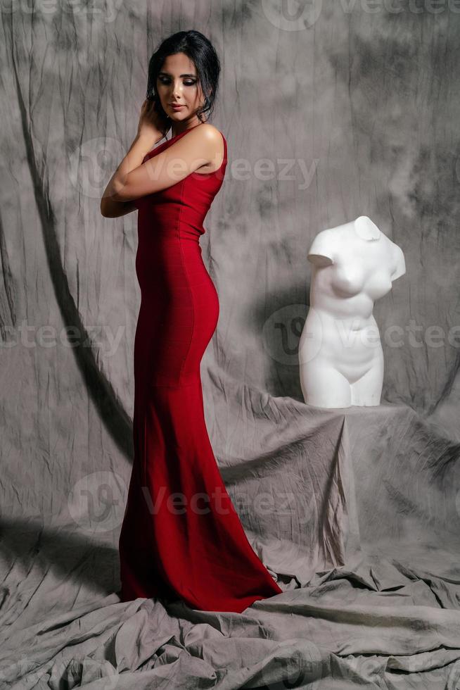 Mädchen im ein rot Abend Kleid auf ein grau Hintergrund foto