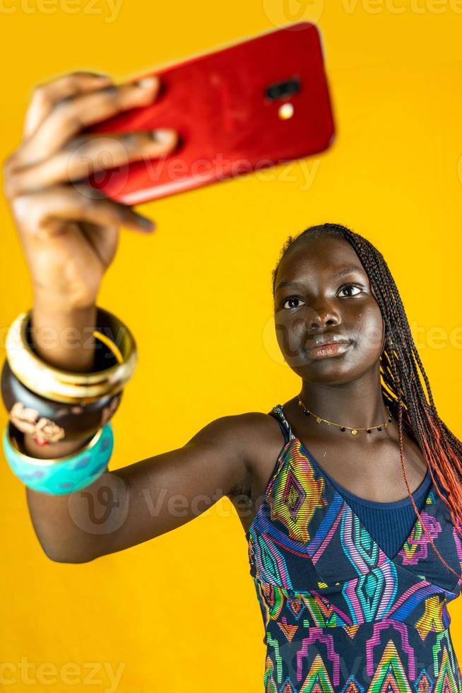 jung afrikanisch amerikanisch weiblich mit traditionell Kleid nimmt ein Selfie foto