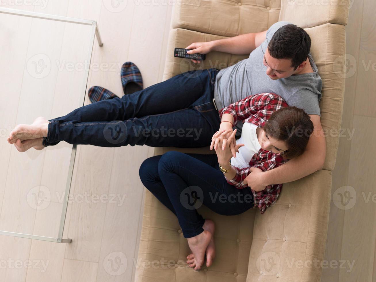 junges Paar auf dem Sofa vor dem Fernseher foto