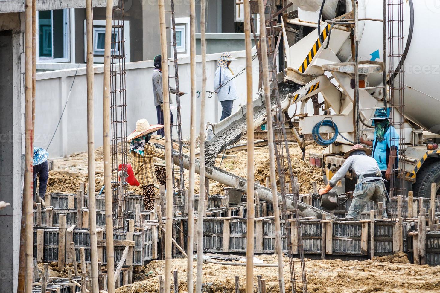 Beton Gießen von Mischer LKW während Konstruktion Arbeiter Verlegung Beton zu das Böden Balken foto