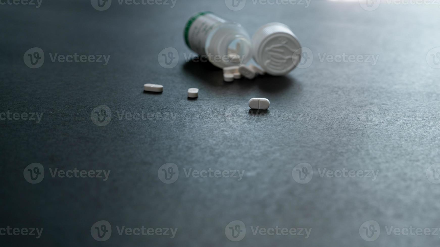 Weiß Tablets Tabletten und verwischen Plastik Pille Flasche auf dunkel Boden. Rezept Drogen. pharmazeutische Industrie. medizinisch Pflege. Medikation zum heilen Erkrankung. Apotheke. klein Weiß Pillen. Dosis empfohlen. foto