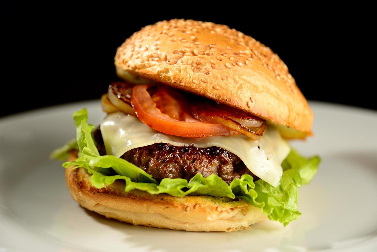 Hamburger mit Zwiebeln, Speck und Salat foto