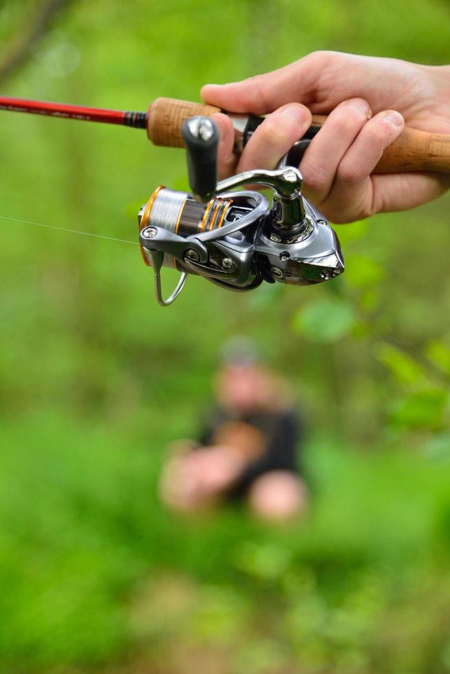 Angelrolle in der Hand des Fischers foto