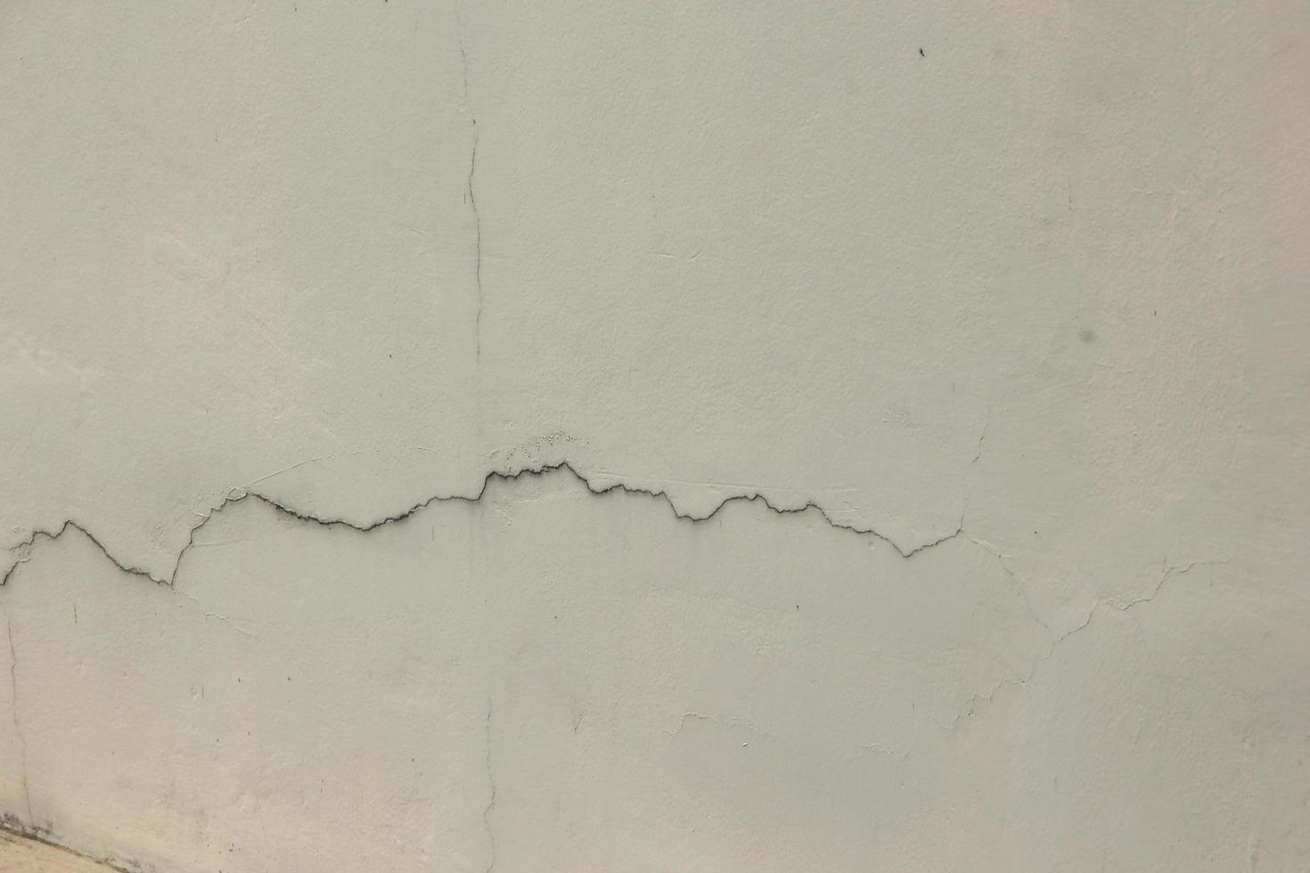 beschädigt Zement Mauer mit Mauer Risse im städtisch Bereich. foto