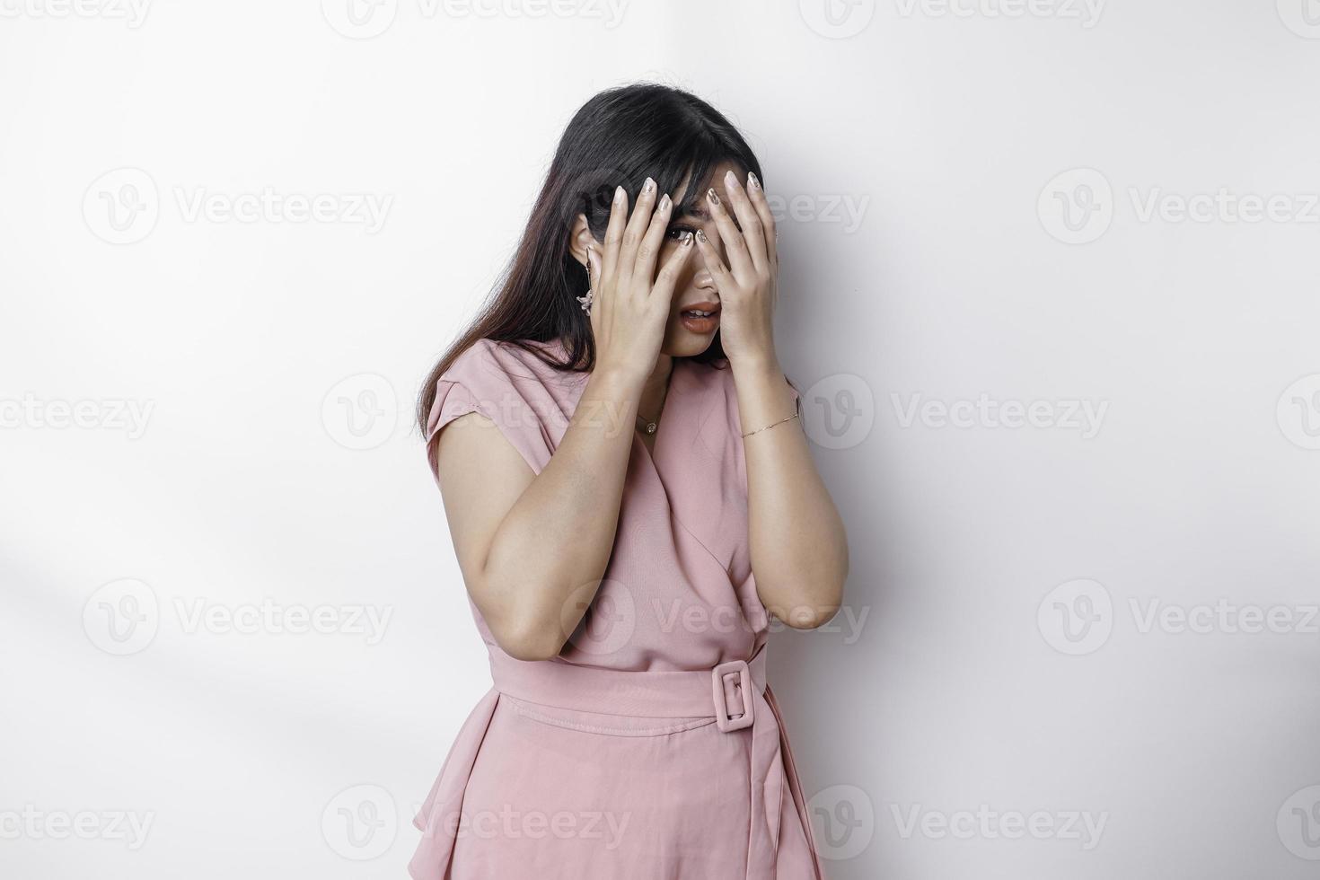 junge asiatische frau isoliert auf weißem hintergrund, sieht deprimiert aus, gesicht bedeckt mit fingern verängstigt und nervös. foto