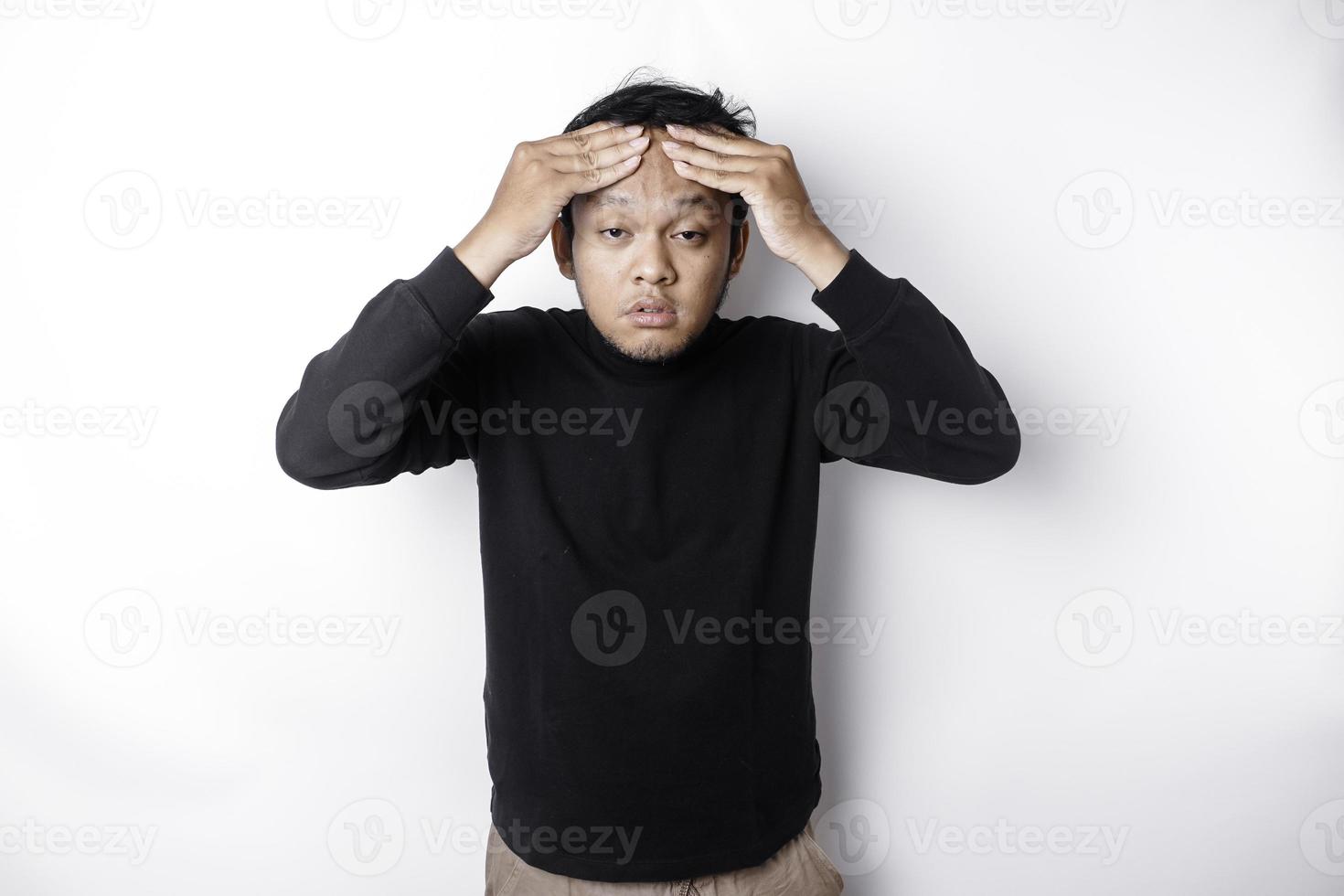ein Porträt von ein asiatisch Mann tragen ein schwarz Hemd isoliert durch Weiß Hintergrund sieht aus deprimiert foto