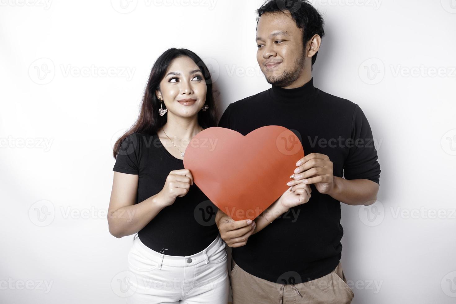 ein jung asiatisch Paar lächelnd und halten rot herzförmig Papier, isoliert durch Weiß Hintergrund foto