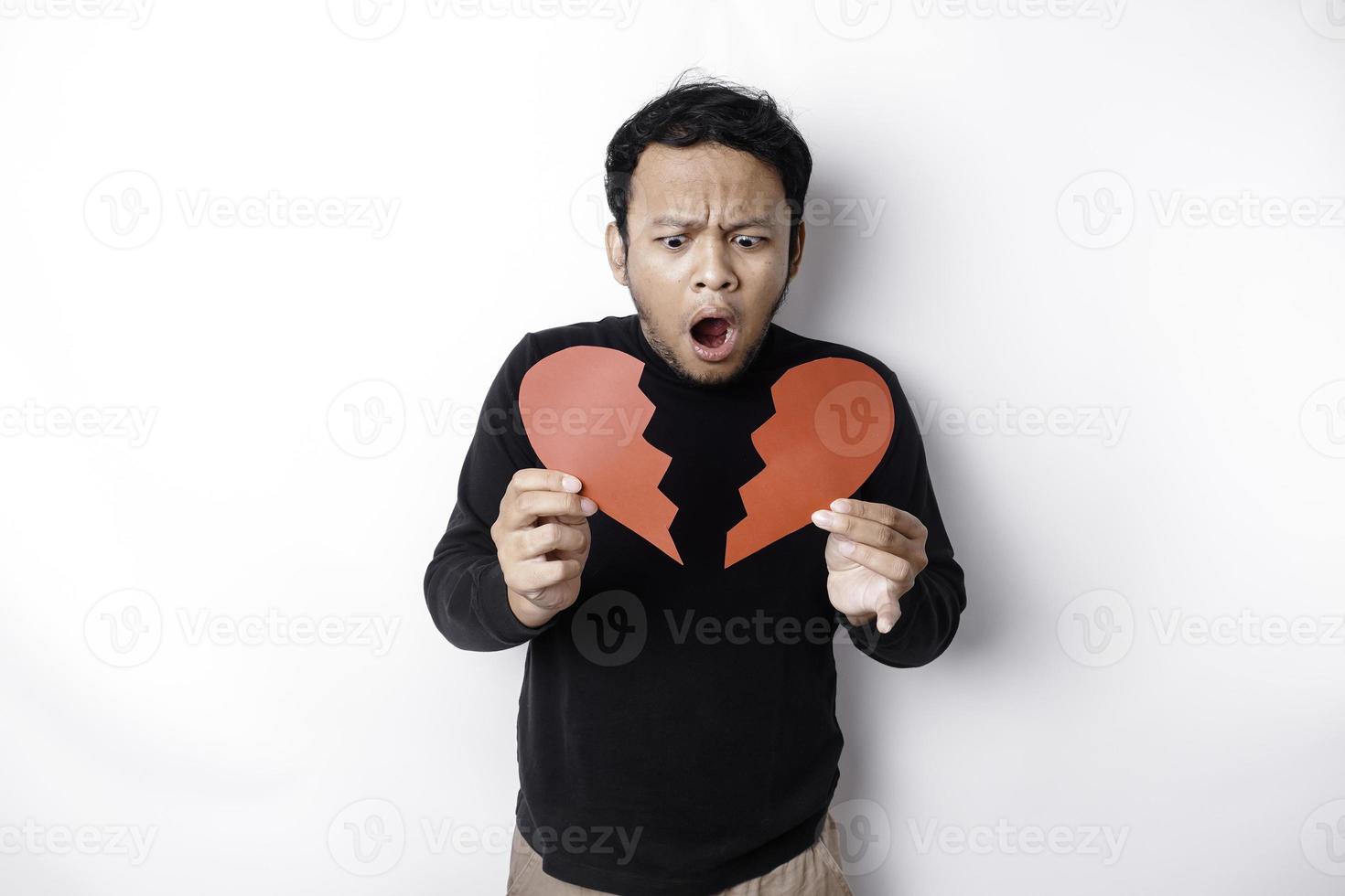 schön jung asiatisch Mann ausgedrückt seine Traurigkeit während halten gebrochen Herz isoliert auf Weiß Hintergrund foto