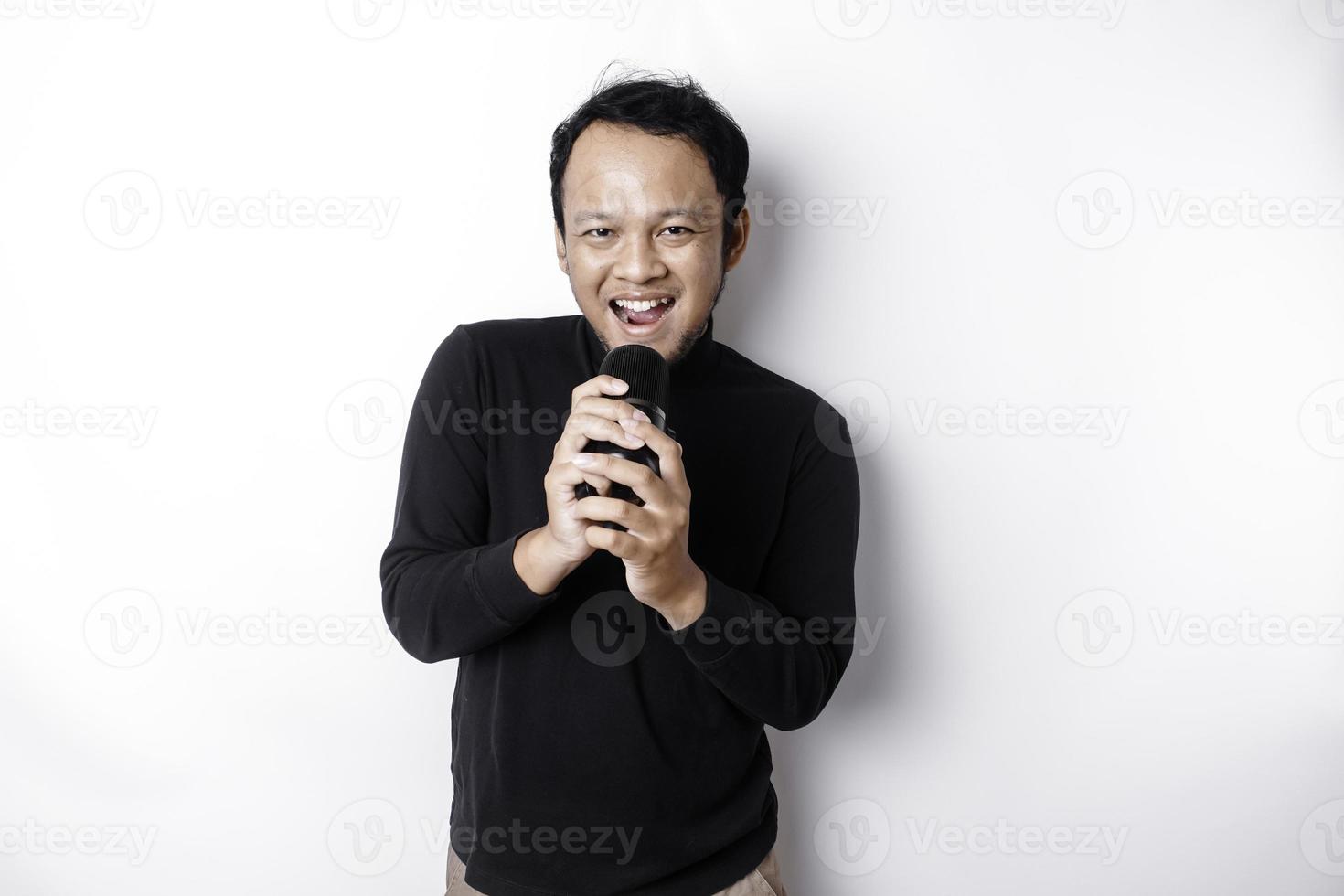 porträt eines sorglosen asiatischen mannes, der spaß beim karaoke hat und im mikrofon singt, während er über weißem hintergrund steht foto