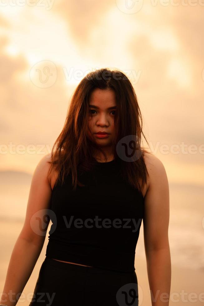 ein asiatisch Teenager Wer ist posieren sexy durch halten ihr Kopf und schwarz Haar auf das Strand foto