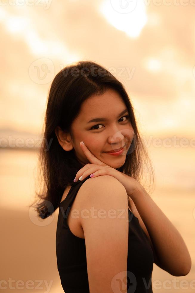 ein asiatisch Teenager Frau mit ein schwarz Hemd und schwarz Haar hat ein süß Gesicht wann sie lächelt und genießt das Aussicht foto