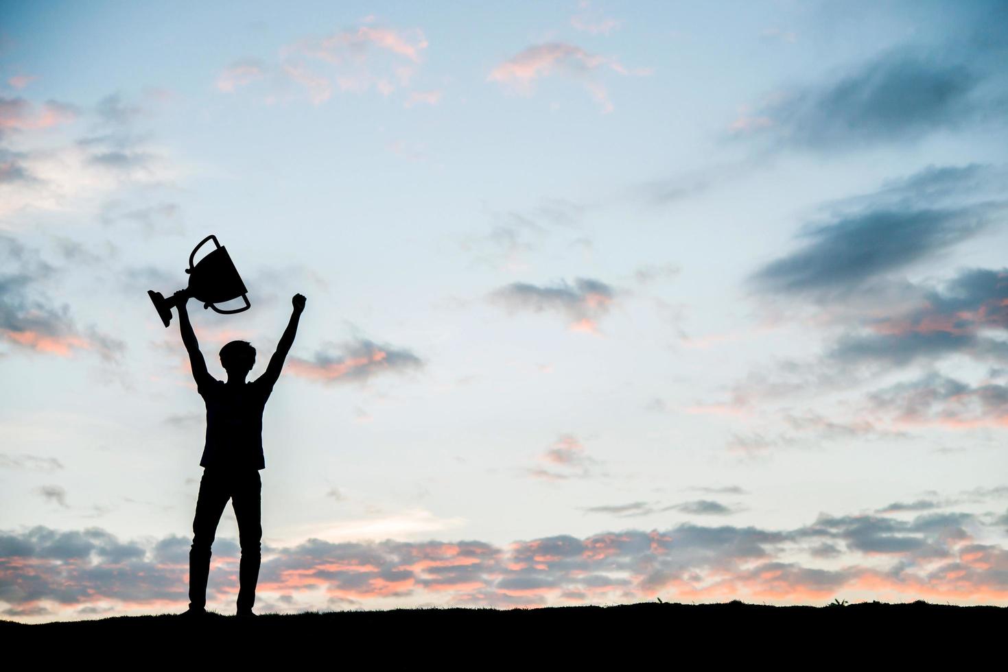 Silhouette Mann hält eine Trophäenschale hoch foto