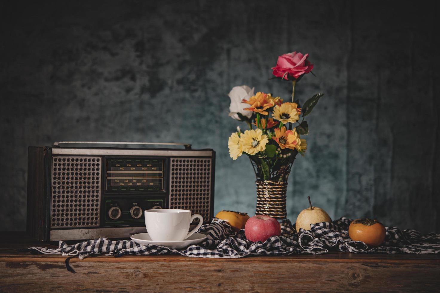 Stillleben mit Vasen, Blumen, Obst, Kaffeetassen und einem Retro-Radioempfänger foto