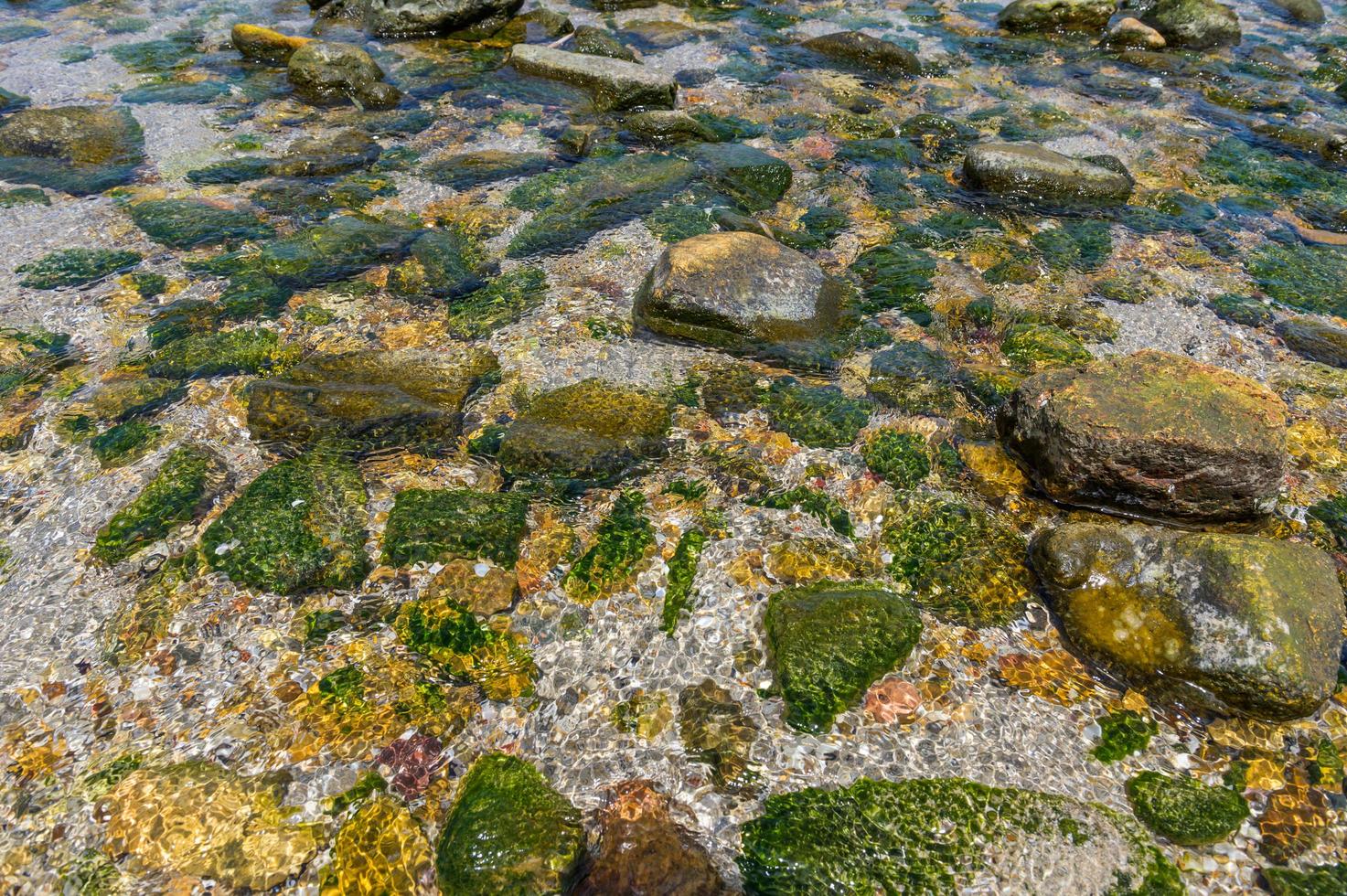 kristallklares Wasser mit vielen Felsen foto