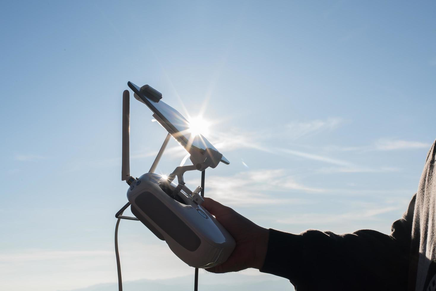 junger Mensch, der eine fliegende Drohne mit Fernbedienung navigiert foto