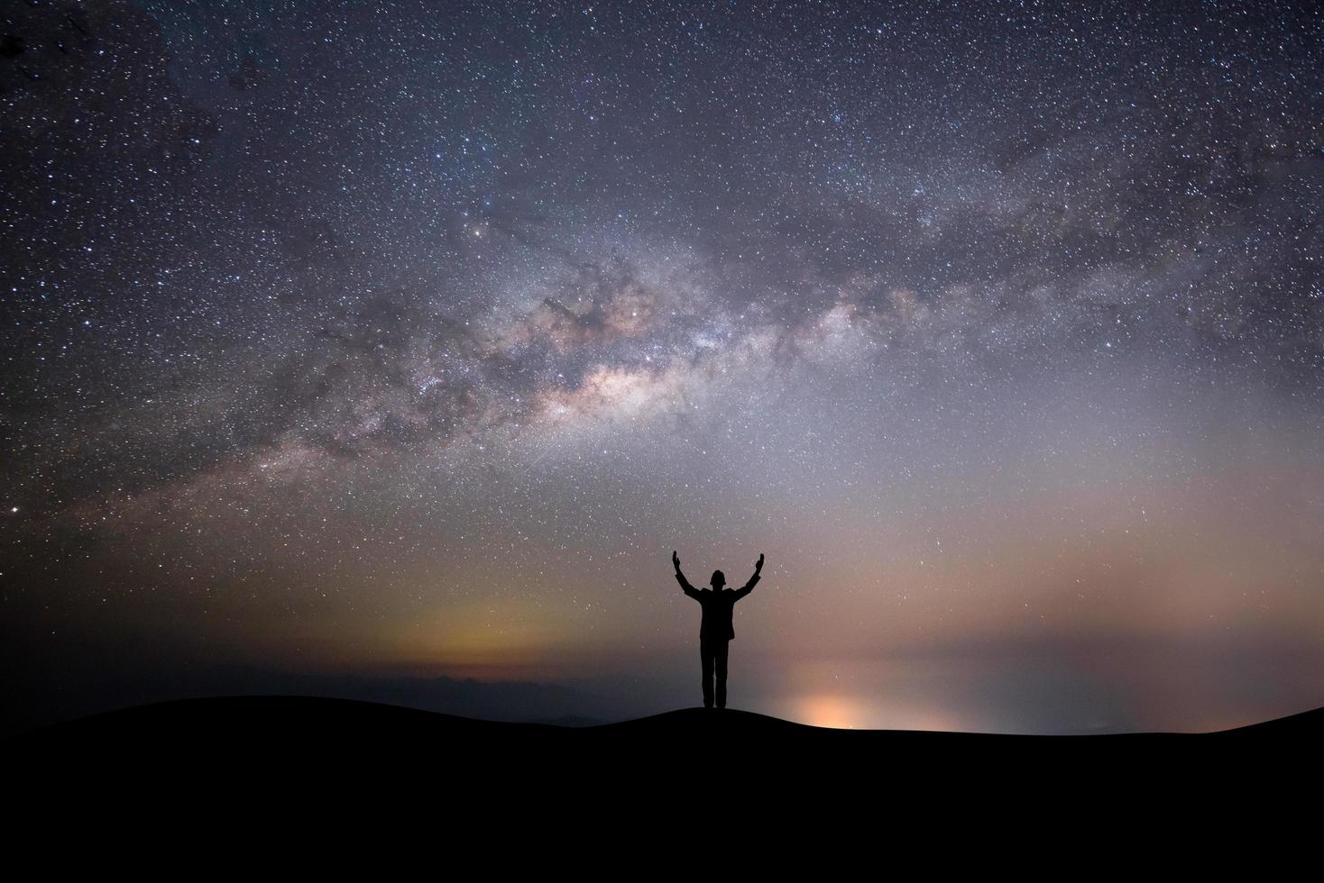 Silhouette einer Person auf einem Hügel mit Sternen foto