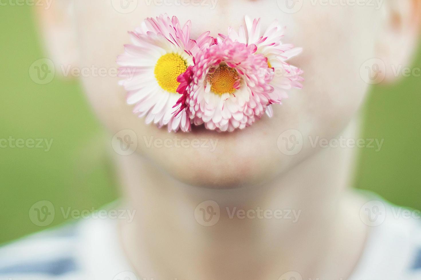 Mann mit ein Gänseblümchen Blume auf ein Grün Hintergrund schließen. Kind Mund mit Blume auf Gras Hintergrund foto