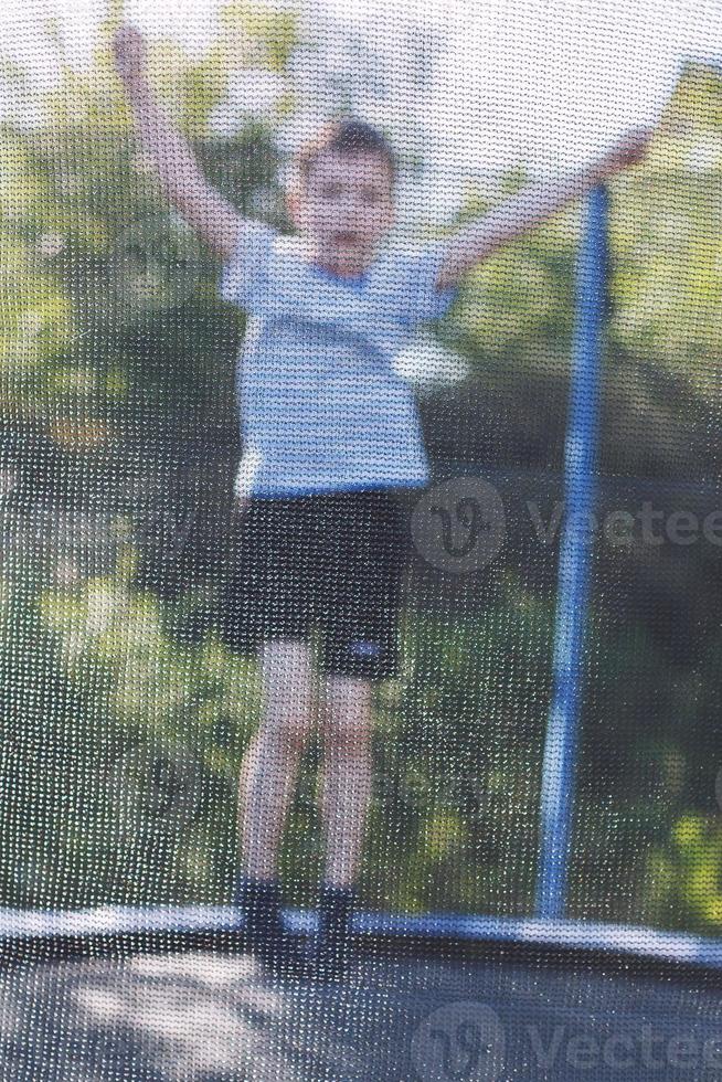 Junge Springen auf Trampolin. das Kind Theaterstücke auf ein Trampolin draussen foto