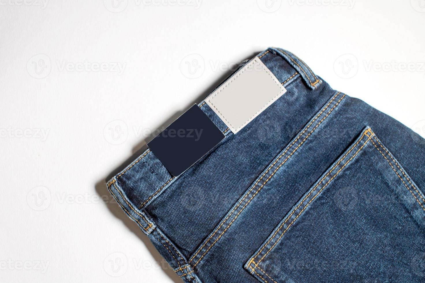 Denim Hose mit ein leeren Leder Etikette auf ein Blau Hintergrund. klassisch zurück Aussicht von Jeans von über mit ein Etikette Layout . foto