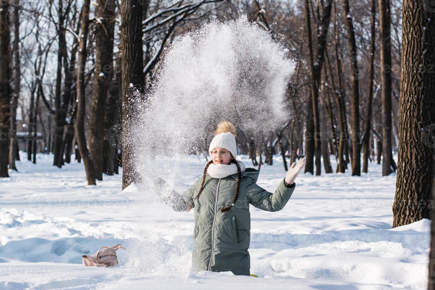 ein Mädchen im Brille und warm Kleider genießt das Schnee im ein Winter Park. Spiele im Natur. foto