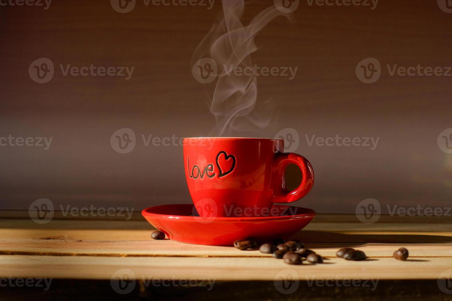 rote Tasse Kaffee auf Holz mit Kaffeebohnen foto