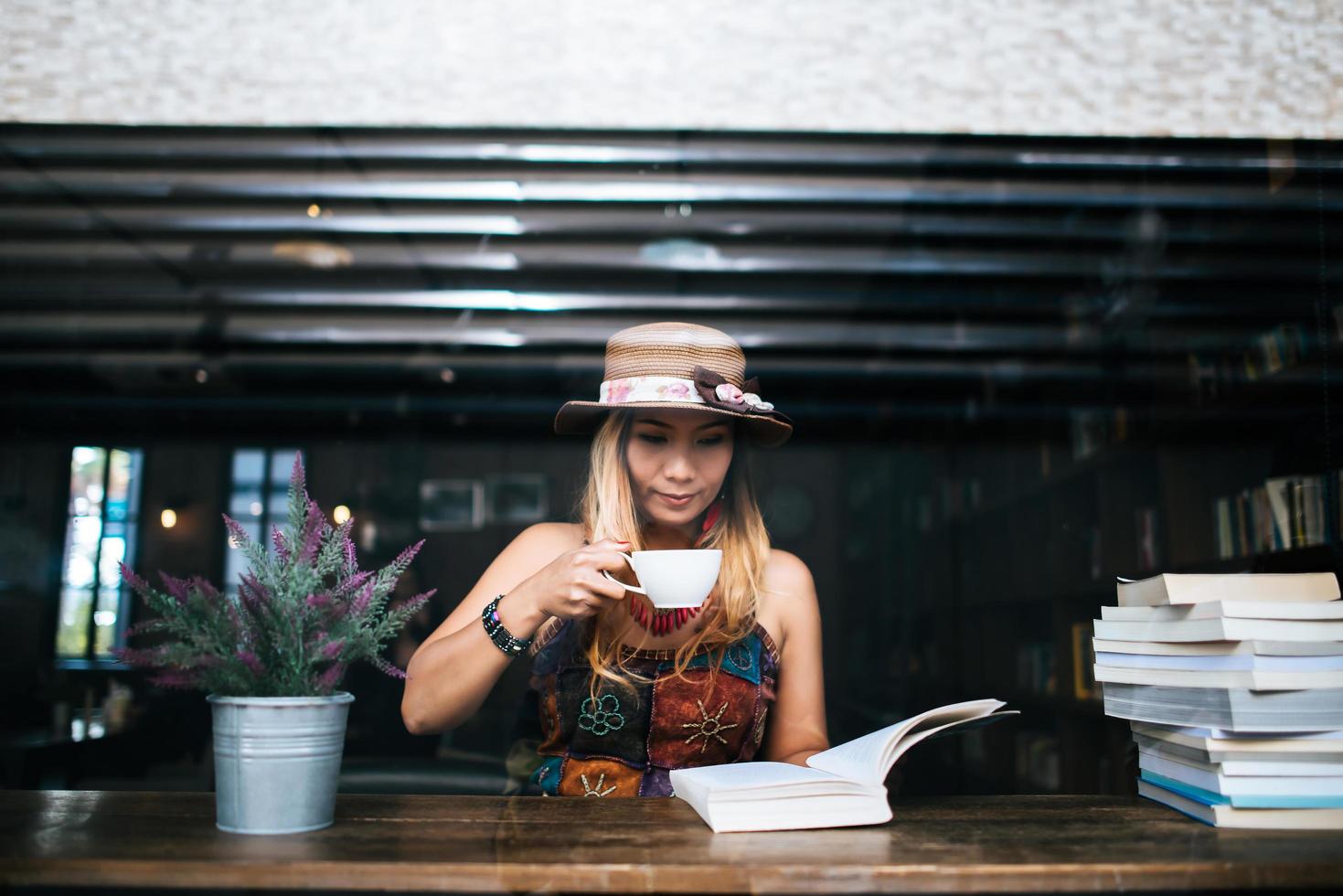 Frau trinkt Cappuccino und liest ein Buch foto