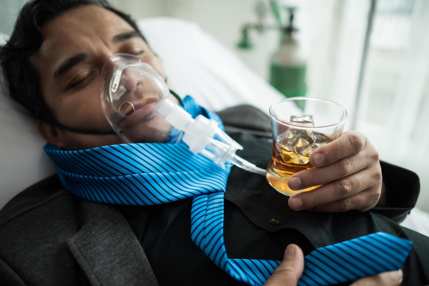 Geschäftsmann trinkt auf Krankenhausbett foto