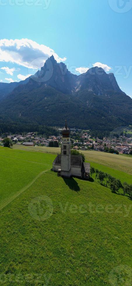 st. Valentin Kastelruth Dorf Kirche im das Sommer- im das Dolomit Alpen. tolle Landschaft mit klein Kapelle auf sonnig Wiese und petz Gipfel beim Kastelruth Kommune. Dolomiten, Süd Tirol, Italien foto