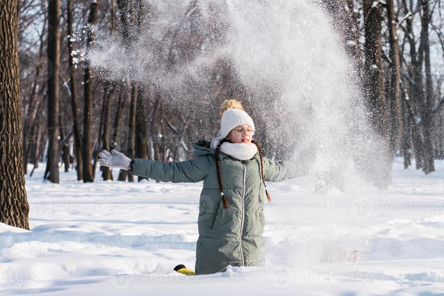 ein Mädchen im Brille und im warm Kleider Theaterstücke mit Schnee im ein Winter Park. Spaziergänge im das Luft. foto