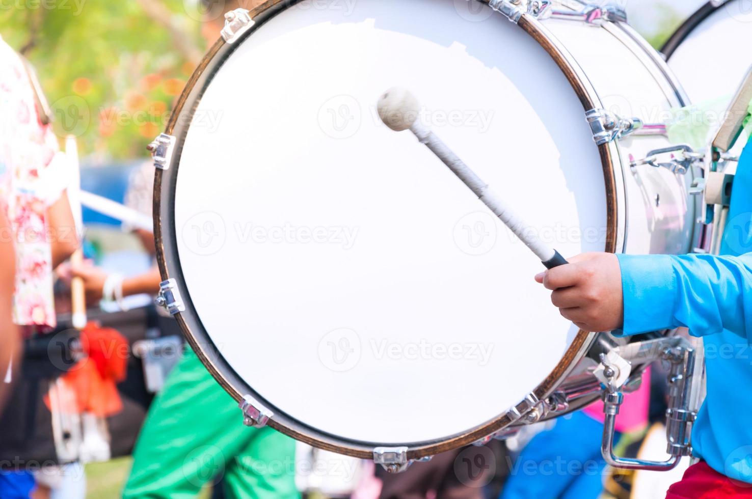 Schlagzeuger im Blau Uniformen ein marschieren Band. Schlagzeuger Theaterstücke groß Trommel im Parade foto