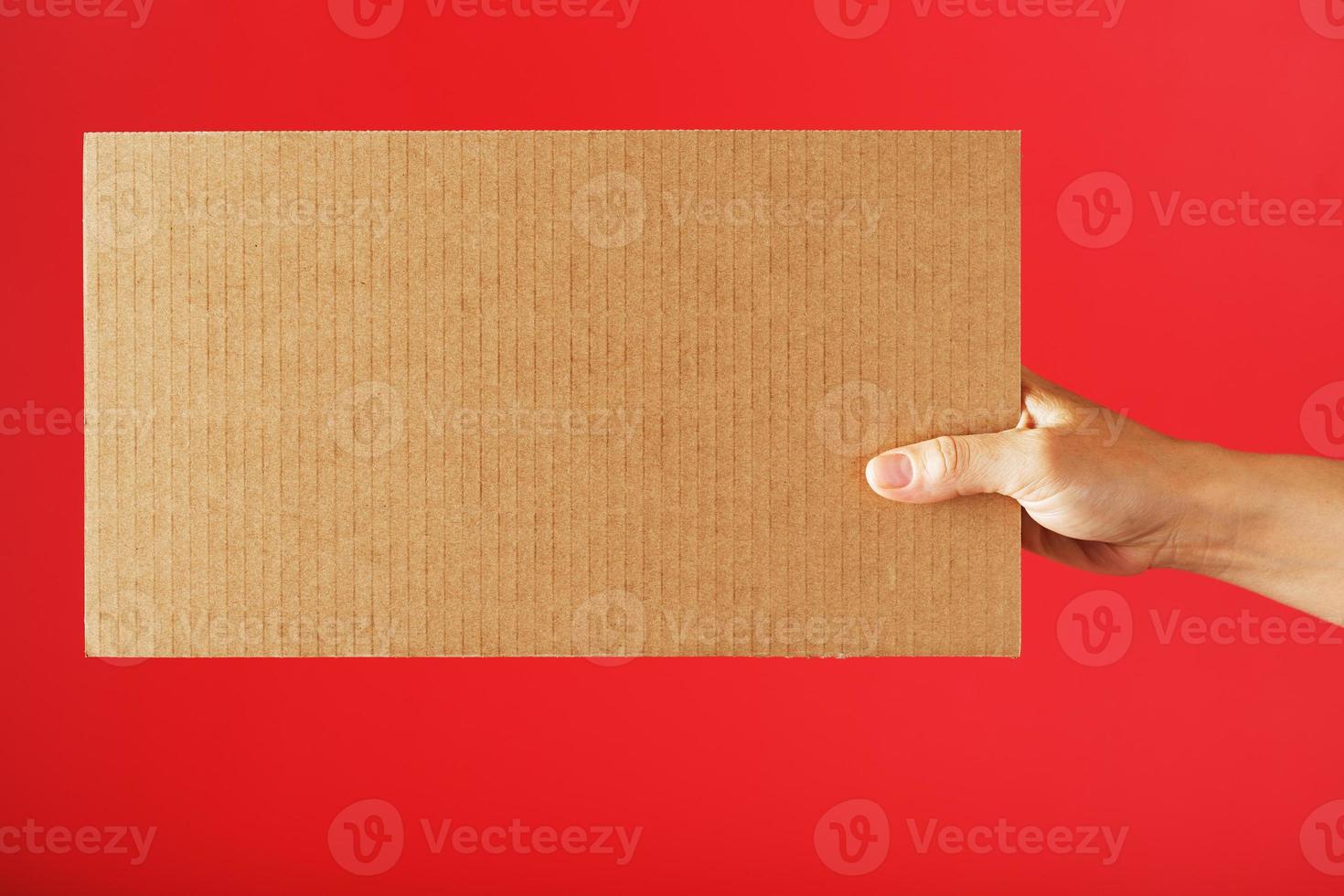 ein leer Blatt von Karton im Ihre Hände auf ein rot Hintergrund. foto