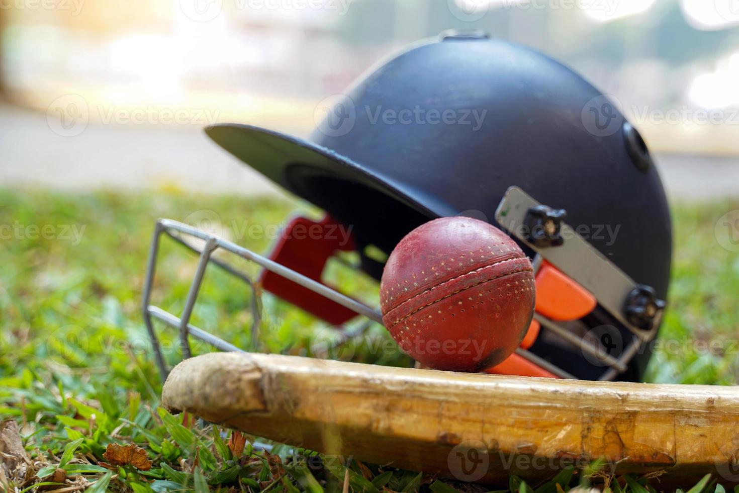 Cricket-Ausrüstung ist ein Cricket-Ball, ein Cricket-Schläger, ein Cricket-Helm auf einem Grashintergrund. weicher und selektiver Fokus. foto