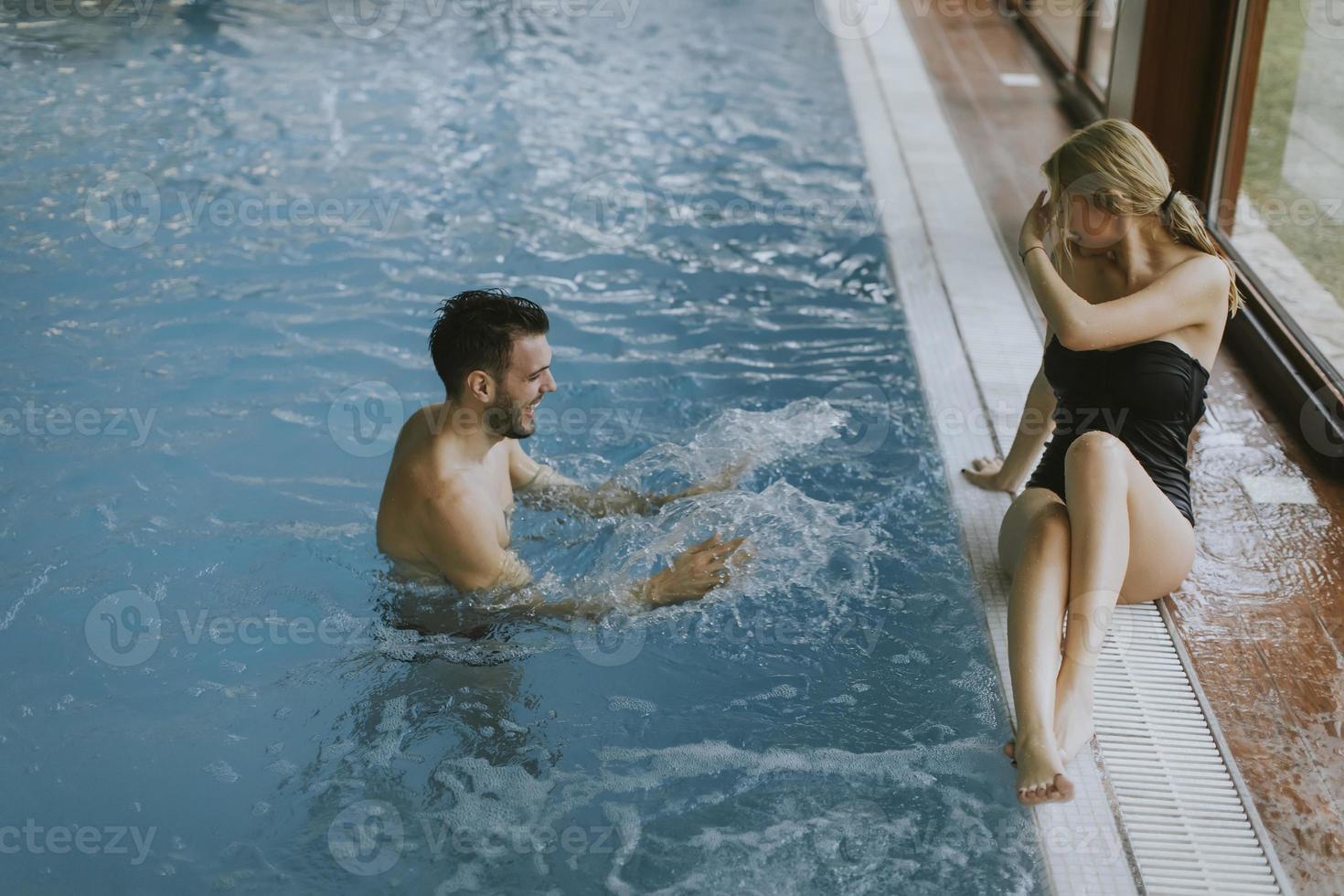 junges Paar, das sich am Pool des Innenpools entspannt foto