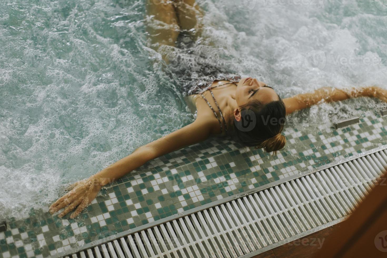 junge Frau, die in der Whirlpool-Badewanne am Pool entspannt foto