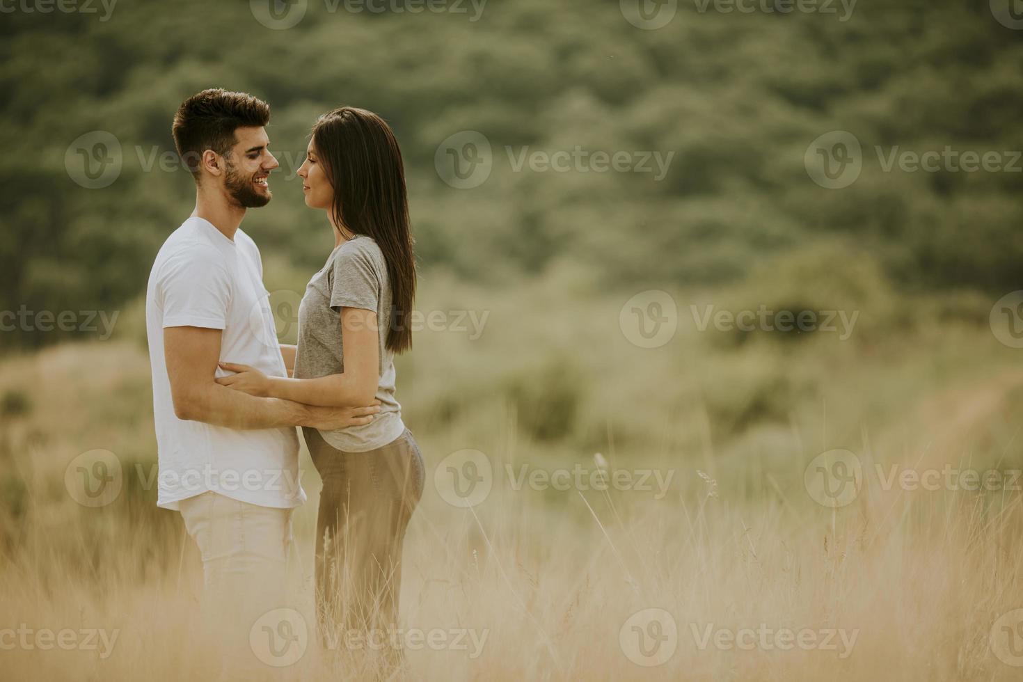 glückliches junges Paar in der Liebe, die durch Grasfläche geht foto