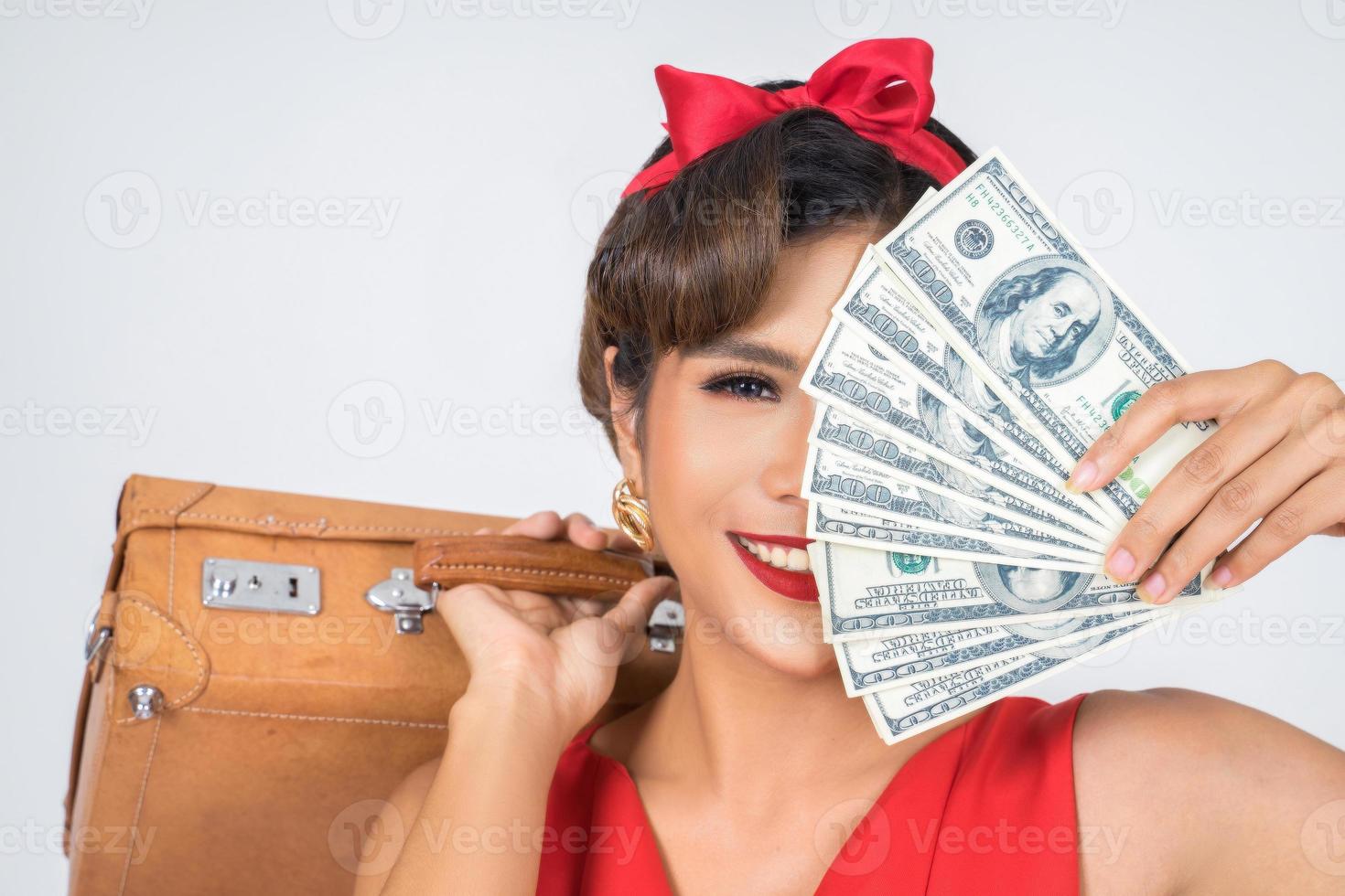 Retro modische Frau hält Gepäck und Geld, um zu reisen foto