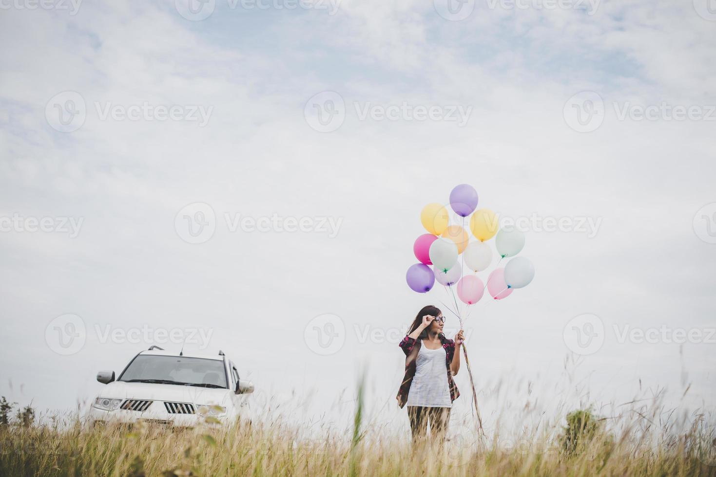 schöne junge Hipsterfrau, die bunte Luftballons draußen hält foto