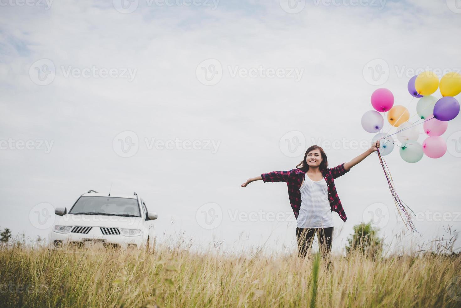 schöne junge Hipsterfrau, die bunte Luftballons draußen hält foto