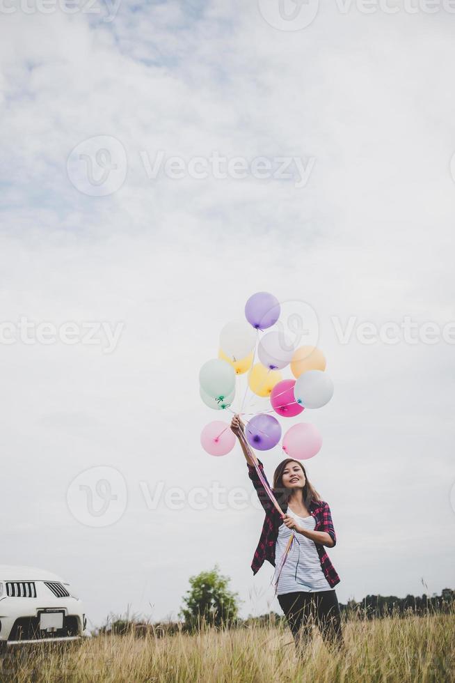 schöne junge Hipsterfrau, die bunte Luftballons draußen hält foto
